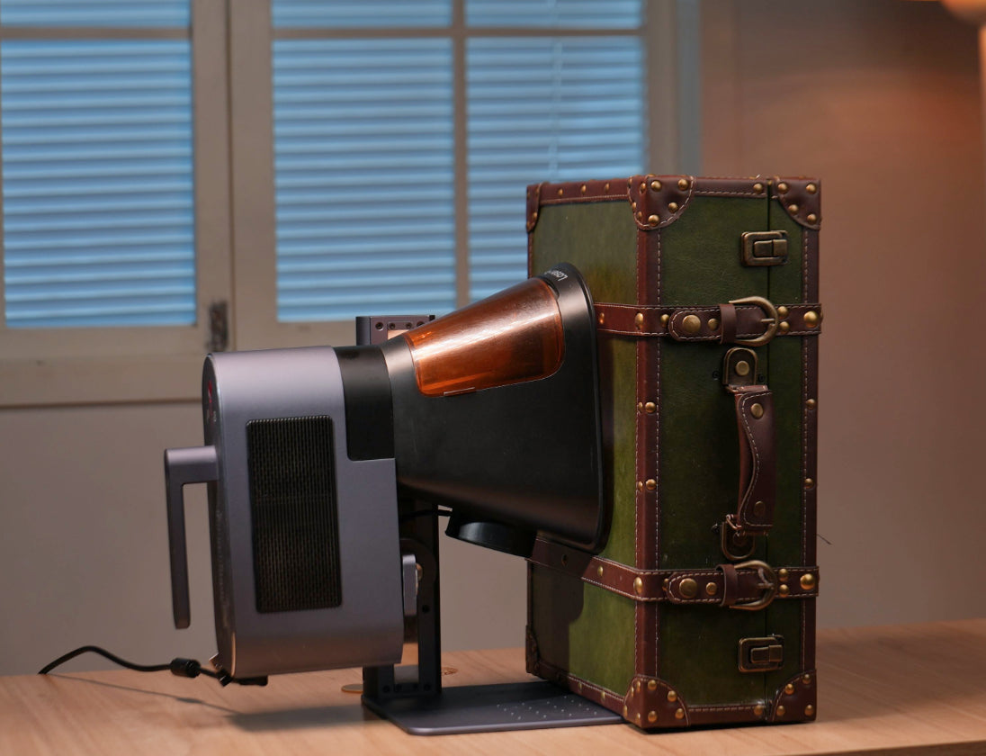 LaserPecker LP5 mounted on a stand, positioned to engrave a vintage suitcase surface, demonstrating its capability to process hard-to-reach areas and diverse surfaces (supporting the "Any Angle, Any Surface" feature).